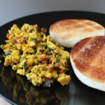Gluten-Free Tofu Scramble on a plate next to gluten-free english muffins.