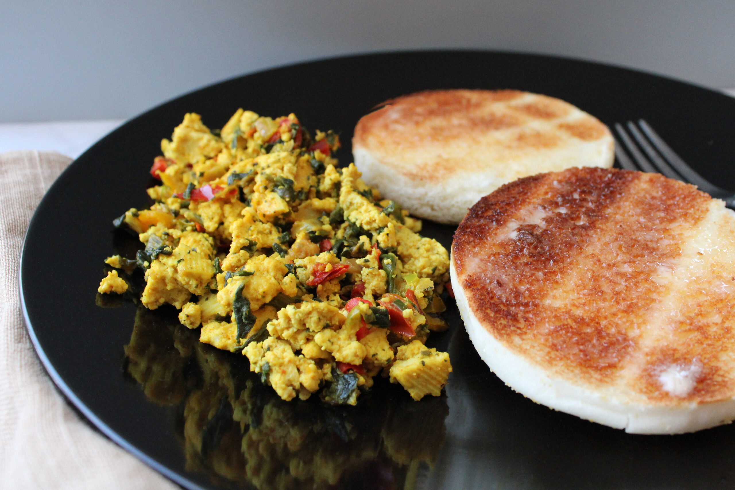 Gluten-Free Tofu Scramble on a plate next to gluten-free english muffins.